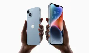 Dwie ręce trzymają jasnoniebieskie iPhone'y 14. Zastanawiasz się, czy oplaca sie kupic iPhone 14?