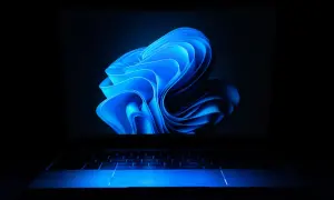 Laptop z niebieskim podświetleniem klawiatury i ekranem z abstrakcyjnym motywem. Dowiedz się, jak ustawić hasło na laptopa, by chronić swoje dane.