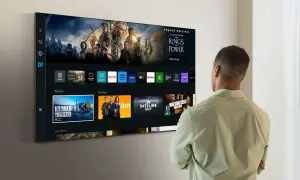 Mężczyzna patrzy na nowoczesny telewizor Samsung z interfejsem Smart TV i ikonami aplikacji.