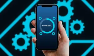 Dłoń trzyma smartfon z ekranem pokazującym pasek postępu aktualizacji i ikonki kół zębatych.