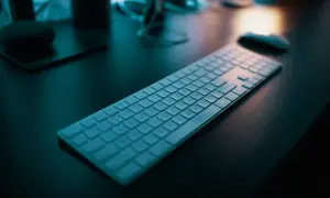 Klawiatura na biurku, gotowa do pracy. Dowiedz się, jak napisać ź na laptopie, by ułatwić sobie pisanie.