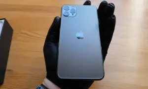 Szary iPhone 11 Pro z potrójnym aparatem, trzymany w czarnej rękawiczce.