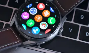 Huawei Watch z kolorowymi ikonami aplikacji na ekranie, leżący na klawiaturze. Dowiedz się, jak zaktualizować Huawei Watch, by cieszyć się nowymi funkcjami.