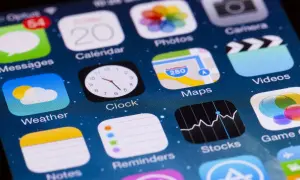 Ekran iPhone'a z ikonami aplikacji, w tym "Stocks", która pokazuje wykresy, sugerując, jakie aplikacje są płatne na iPhone.