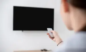 Osoba trzyma pilot, by dowiedzieć się, jak zaktualizować telewizor LG.