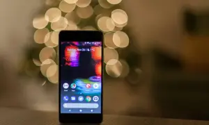 Smartfon z kolorową tapetą i ikonami aplikacji na tle rozmytych światełek.