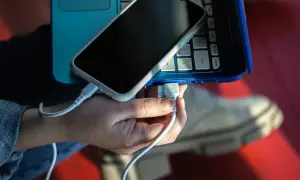 Dłoń podłącza kabel USB telefonu do laptopa, pokazując, jak połączyć telefon z laptopem.