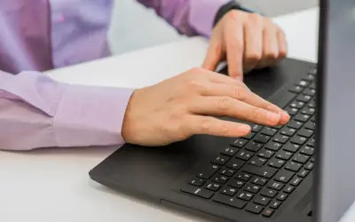 Dłonie piszące na klawiaturze laptopa.