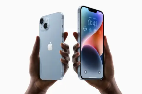 Dwie ręce trzymają jasnoniebieskie iPhone'y 14. Zastanawiasz się, czy oplaca sie kupic iPhone 14?