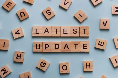 Drewniane klocki z literami tworzą napis "LATEST UPDATE". Dowiedz się, jak zaktualizować sterowniki w komputerze, aby cieszyć się najnowszymi funkcjami.