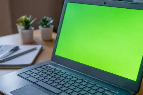Zielony ekran laptopa, obok notatnik z długopisem. Czy to chromebook czy laptop?