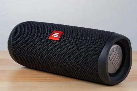 Czarny głośnik JBL na drewnianym blacie. Dowiedz się, jak podłączyć głośnik bluetooth z laptopem, by cieszyć się muzyką.