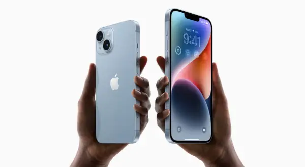 Dwie ręce trzymają jasnoniebieskie iPhone'y 14. Zastanawiasz się, czy oplaca sie kupic iPhone 14?
