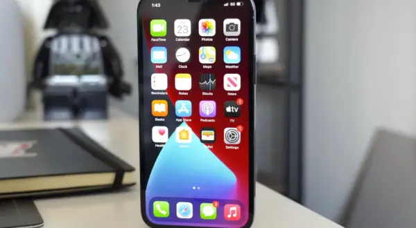 iPhone 11 z widocznym wskaźnikiem 5G na ekranie, na biurku obok figurki Dartha Vadera.