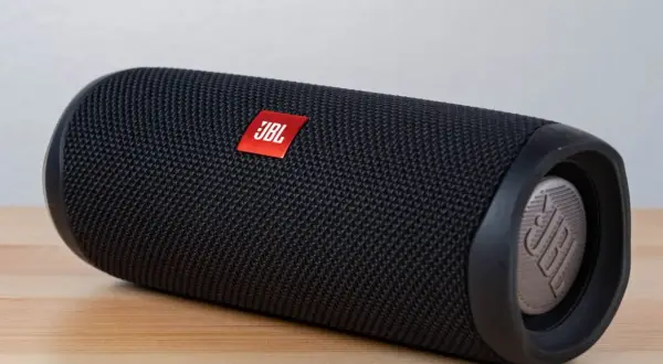 Czarny głośnik JBL na drewnianym blacie. Dowiedz się, jak podłączyć głośnik bluetooth z laptopem, by cieszyć się muzyką.