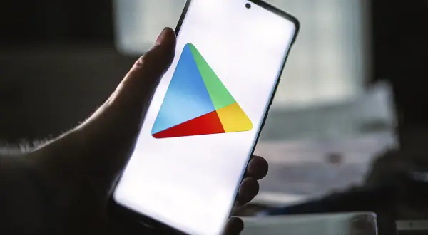 Dłoń trzyma smartfon z widocznym logo Sklepu Google Play.
