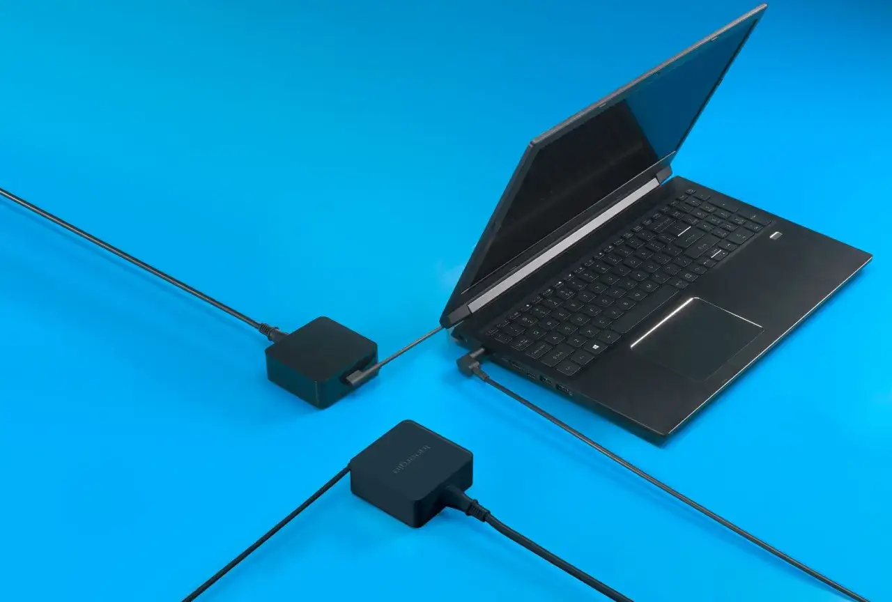 Czarny laptop podłączony do dwóch zasilaczy. Zastanawiasz się, ile prądu zużywa laptop na godzinę?
