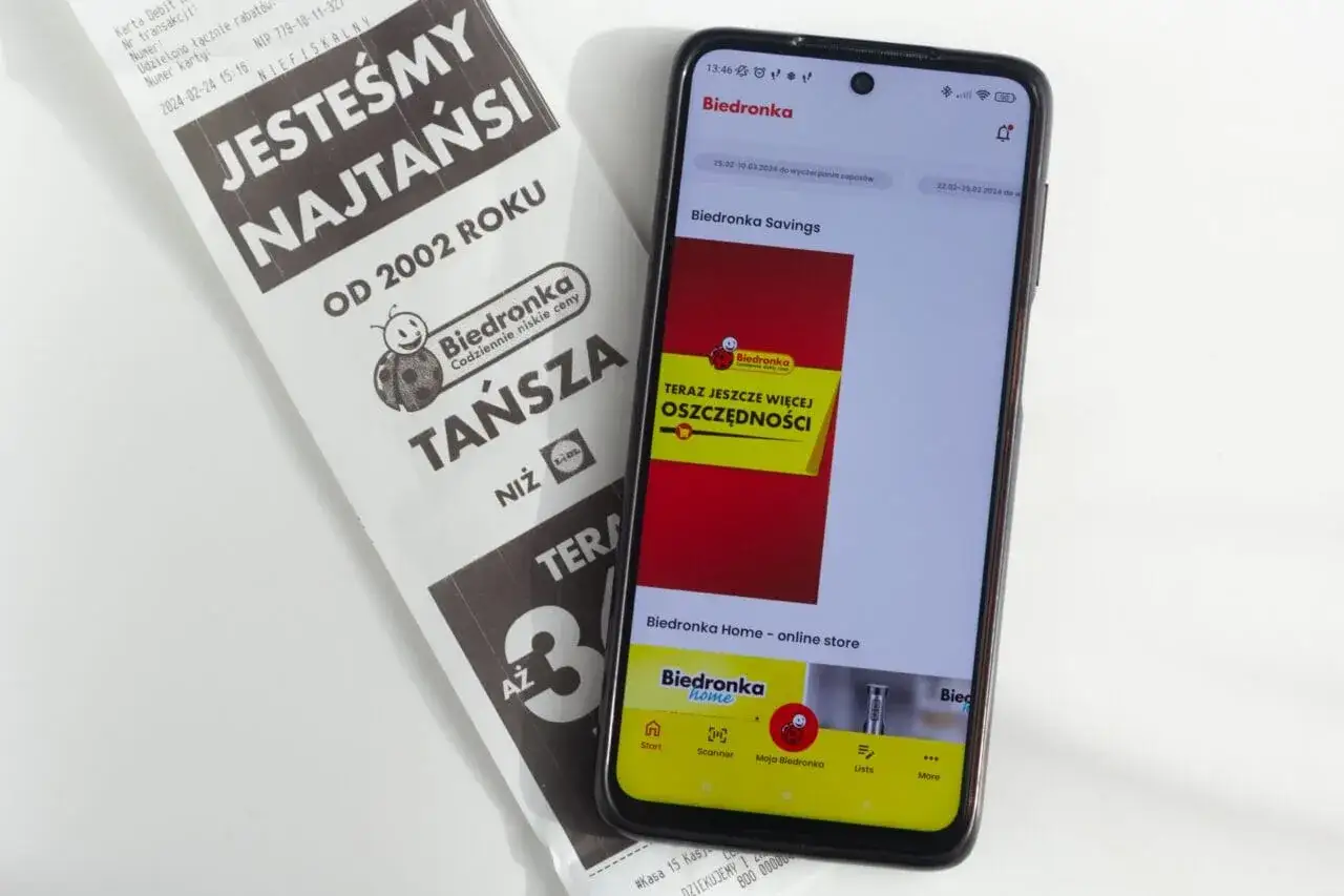 Na ekranie telefonu widać aplikację Biedronka, a obok paragon z hasłem