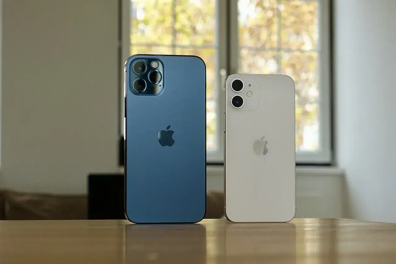 Dwa iPhone'y: niebieski iPhone 12 Pro i biały iPhone 13. Zastanawiasz się, czy etui iPhone 12 pasuje do 13?