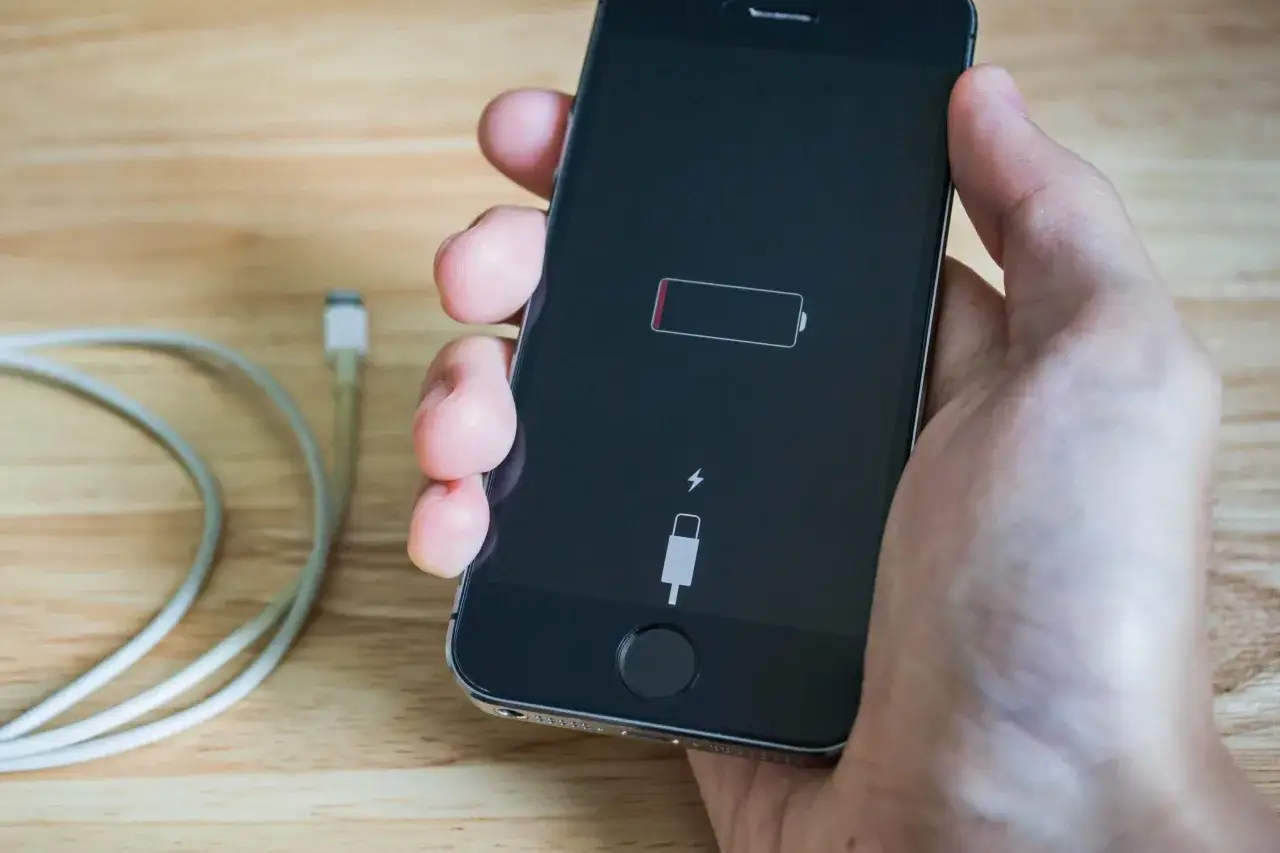 iPhone 8 z rozładowaną baterią i kablem Lightning. Aby włączyć iPhone 8, podłącz go do ładowarki.