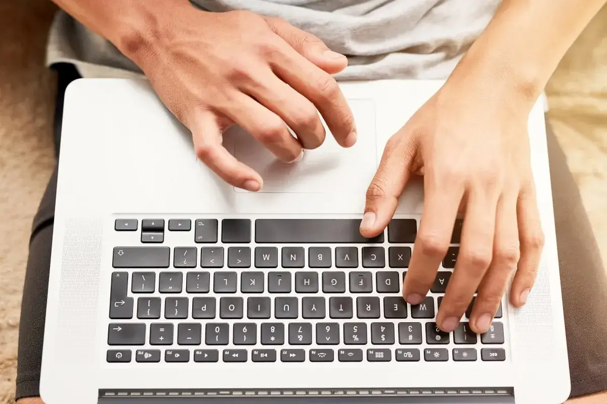 Dłonie na klawiaturze laptopa. Dowiedz się, jak przywrócić ustawienia klawiatury w laptopie, gdy coś pójdzie nie tak.