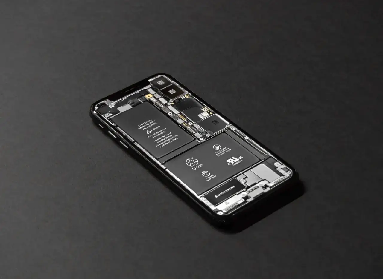 Rozłożony iPhone z widocznymi bateriami. Dowiedz się, jak dbać o baterie iPhone, by służyły dłużej.