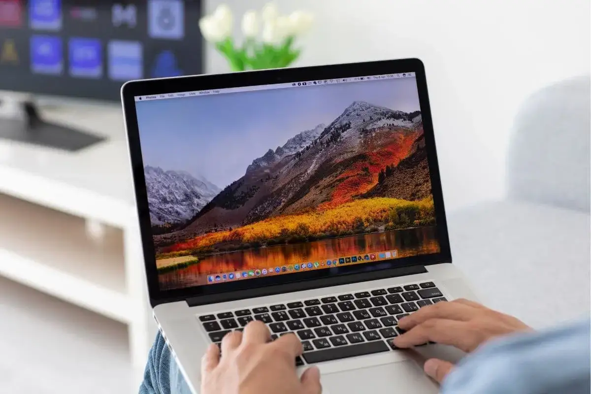 Osoba pisze na laptopie z pięknym widokiem g&oacute;r. Chcesz wiedzieć, jak zrobić screena na laptopie?