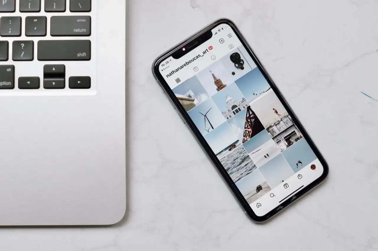 Telefon z Instagramem obok klawiatury laptopa. Dowiedz się, jak połączyć telefon z laptopem, by łatwo przesyłać zdjęcia.
