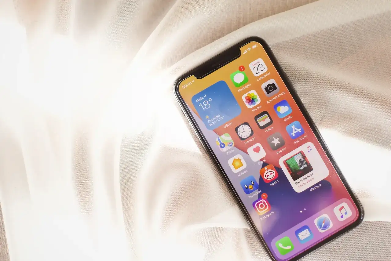 iPhone z widżetem pogody i ikonami aplikacji. Dowiedz się, jak zaktualizować iOS, aby cieszyć się nowymi funkcjami.