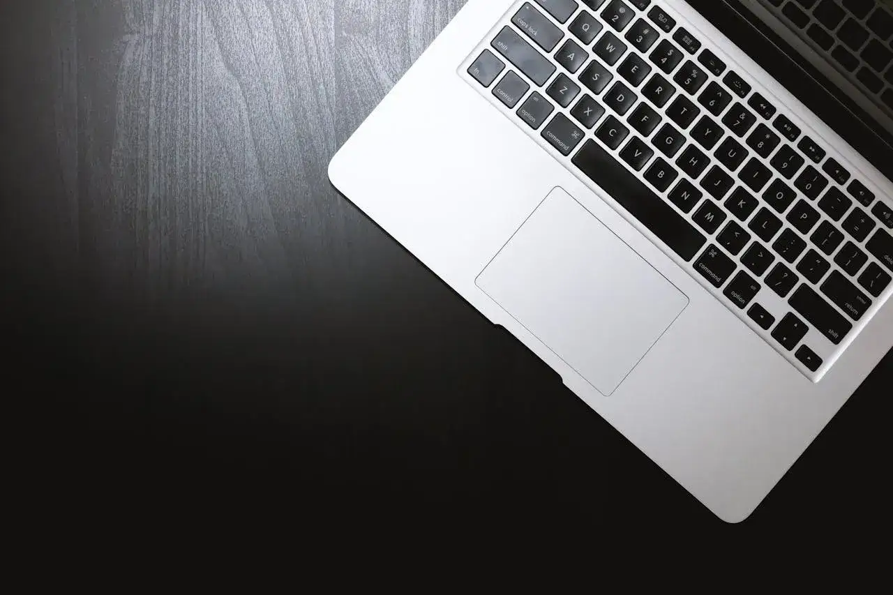 Klawiatura laptopa z widocznym touchpadem. Dowiedz się, jak włączyć dźwięk w laptopie na klawiaturze, szukając ikon głośności.