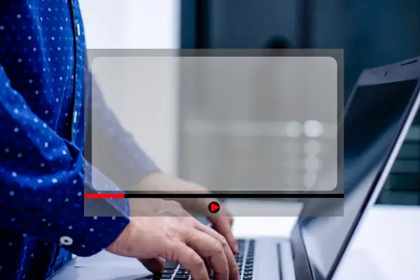 Osoba pisze na laptopie, a na ekranie widoczny jest odtwarzacz wideo. Dowiedz się, jak zmniejszyć ekran w przeglądarce, aby wygodniej oglądać.